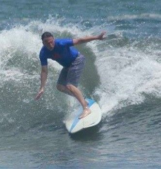 Man in blue shirt surfing in the ocean